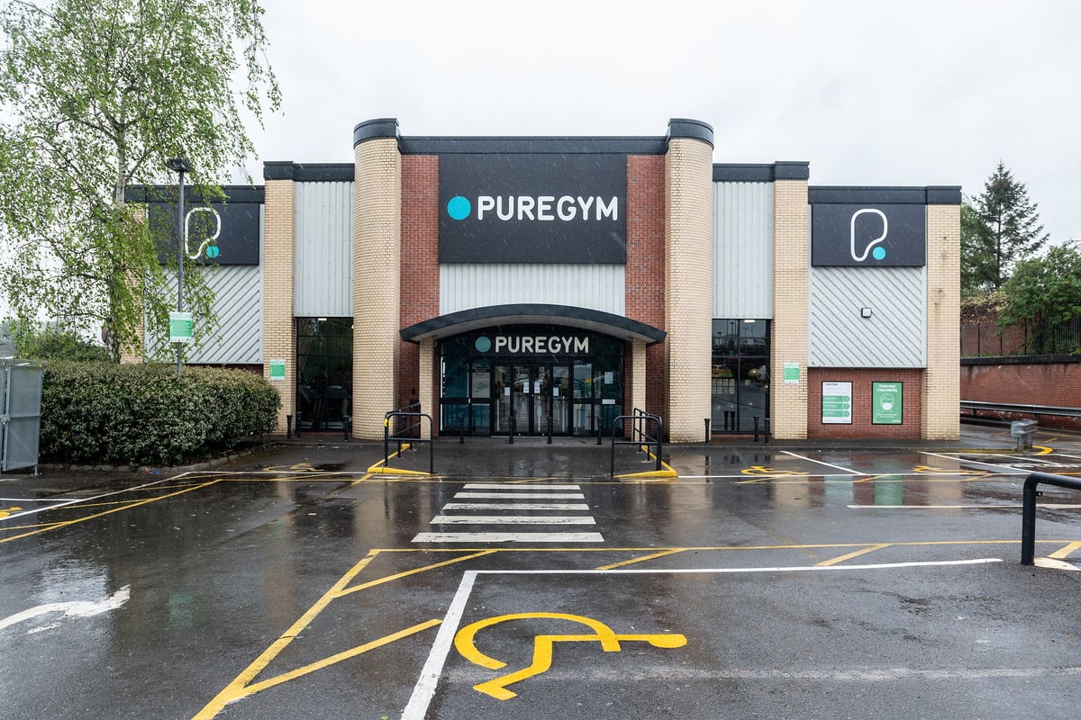 PureGym Stockport North: Gym entrance with parking lot, brick and glass exterior.