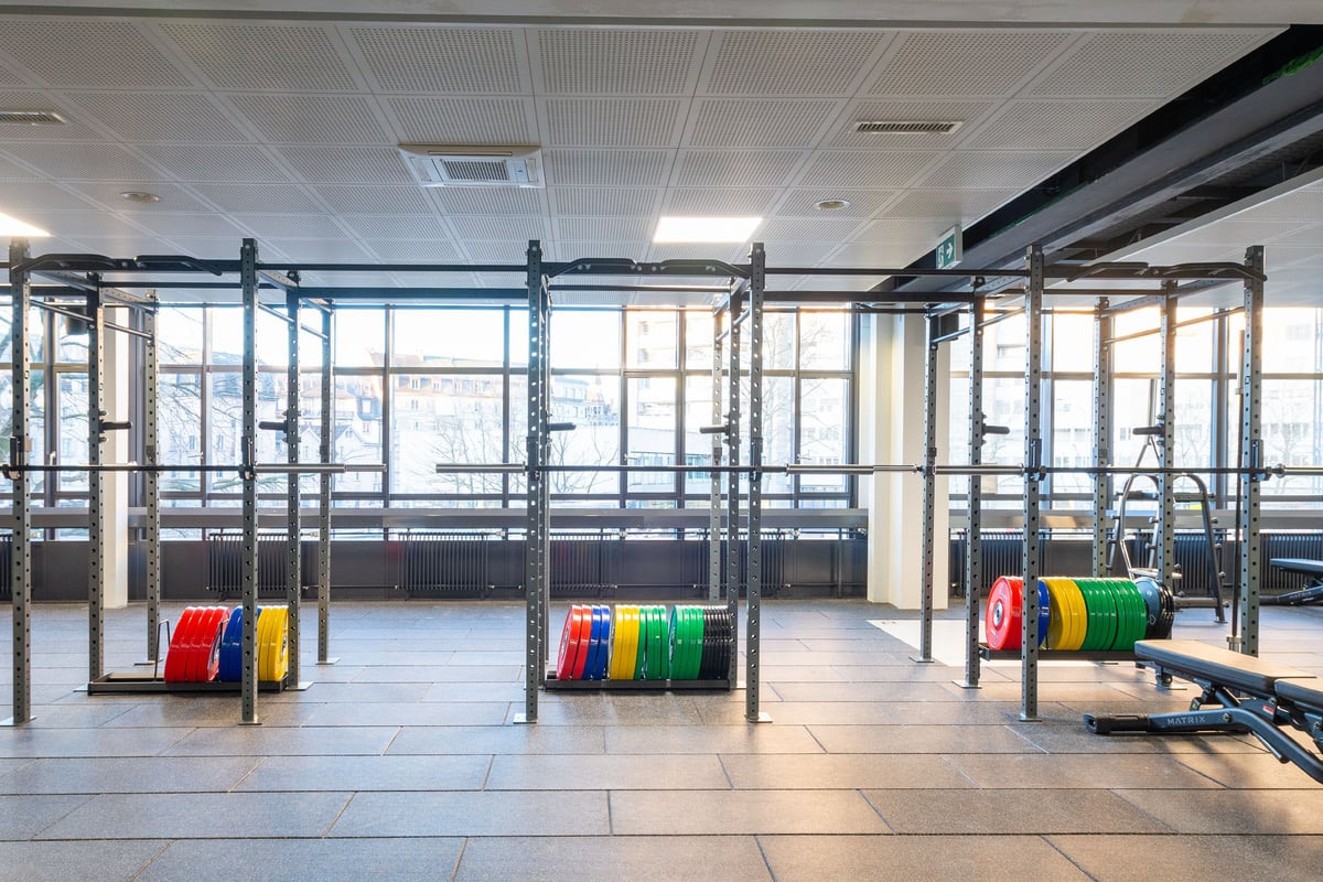 Racks de squat de la gym Lochergut avec disques colorés et fenêtres panoramiques