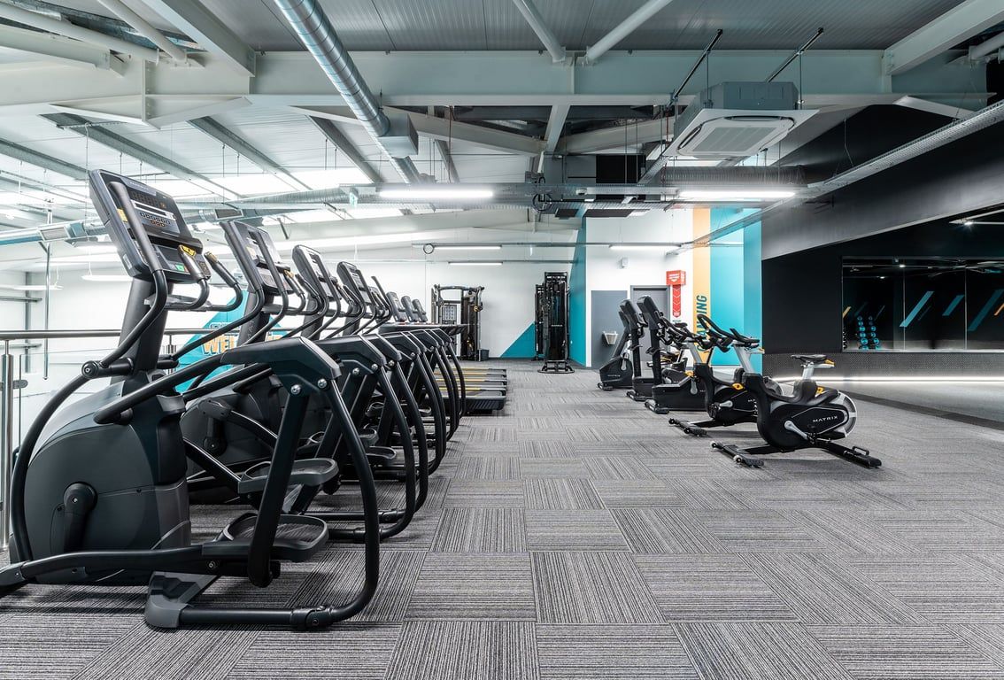 PureGym Ormskirk: Rows of elliptical machines, treadmills, and weight racks inside a brightly lit gym space.