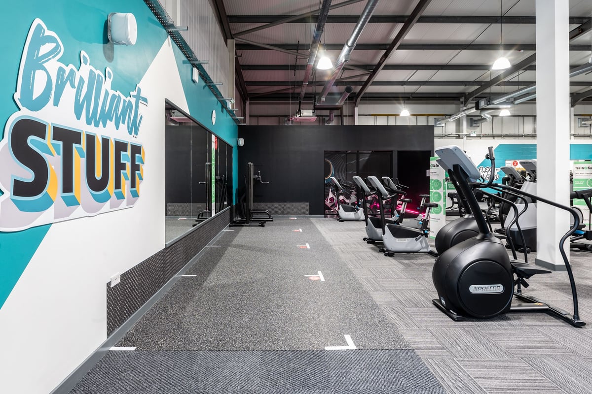 PureGym Swindon Stratton: Rows of treadmills, stationary bikes, and weight machines in a modern gym setting.