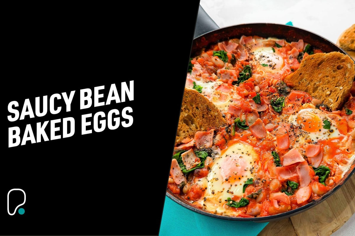 Baked eggs in tomato sauce with spinach, beans, ham, black pepper, and toasted bread.