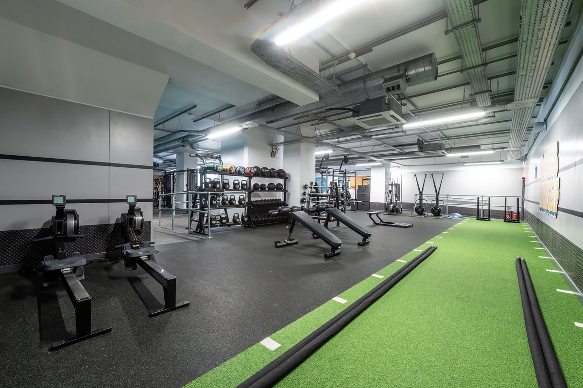 PureGym Stevenage: Weights racks, benches, turf area, resistance bands, rubberized floors in a gym studio.