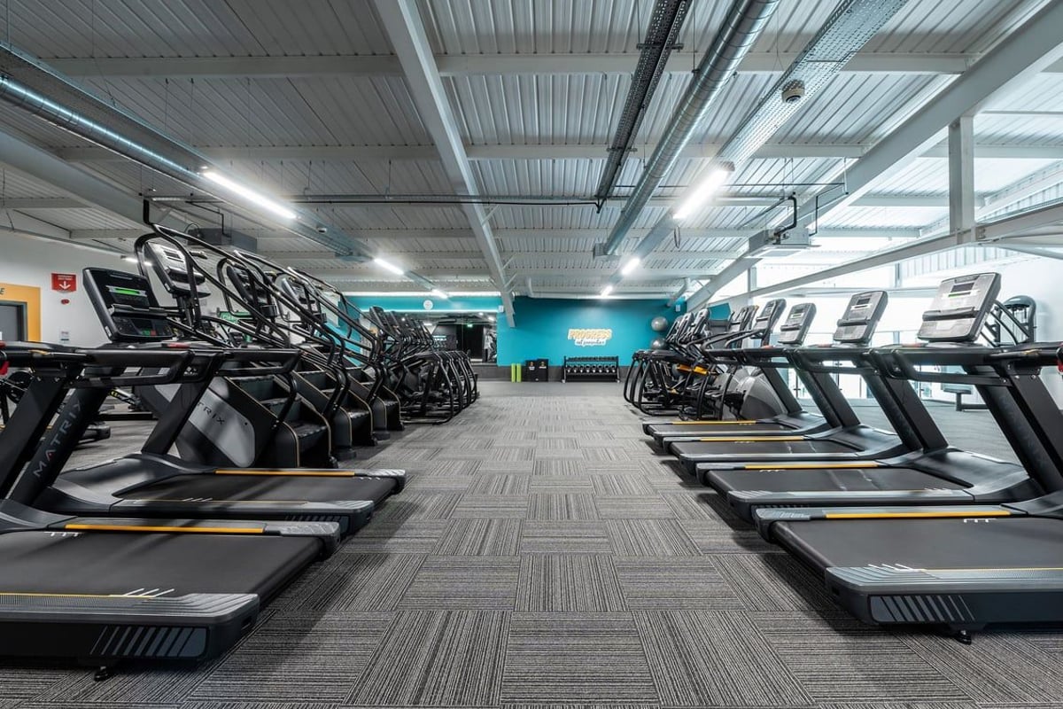 PureGym Cheshunt Brookfield Shopping Park: Rows of treadmills and stationary bikes in a brightly lit gym studio with murals.