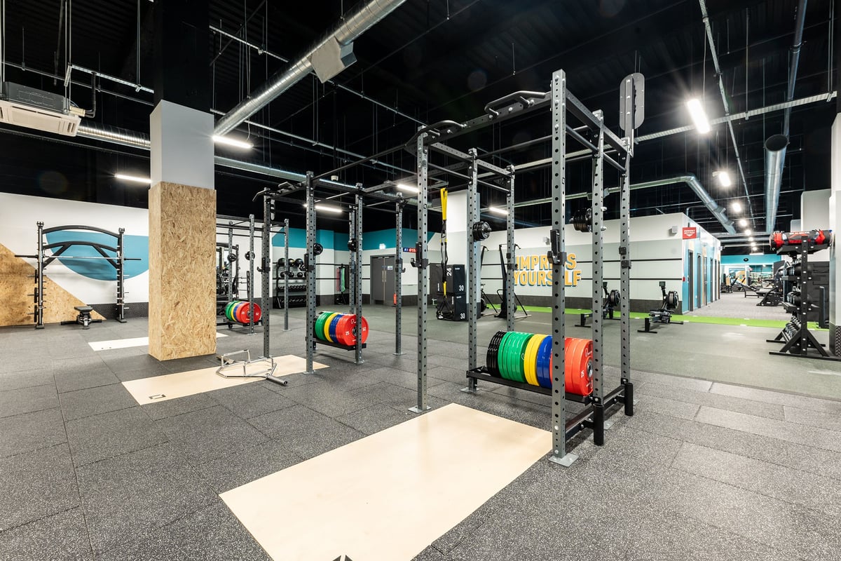 PureGym Hatfield: Racks with weightlifting bars, bumper plates in vibrant hues, workout platforms, overhead rigging.