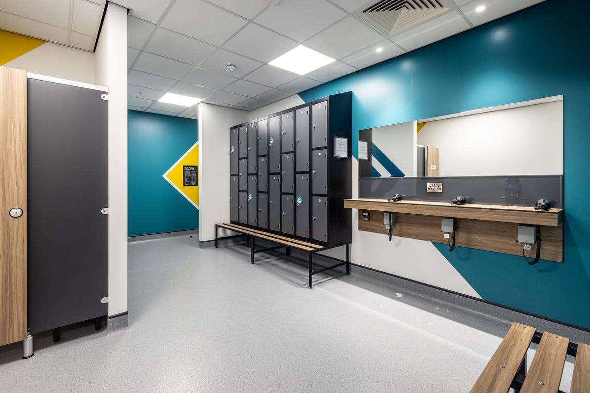 PureGym Washington: Locker room with cubicles, benches, and wall-mounted sinks.
