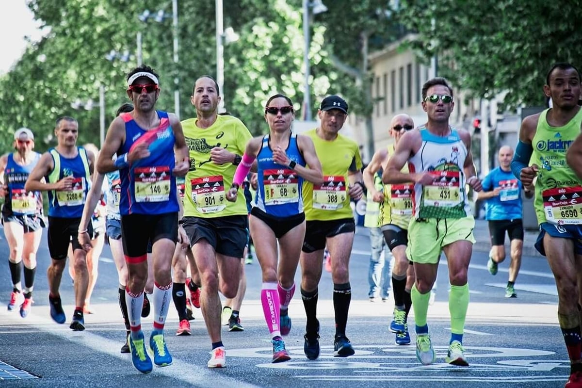 Group of runners in colourful sportswear competing in marathon on tree-lined street