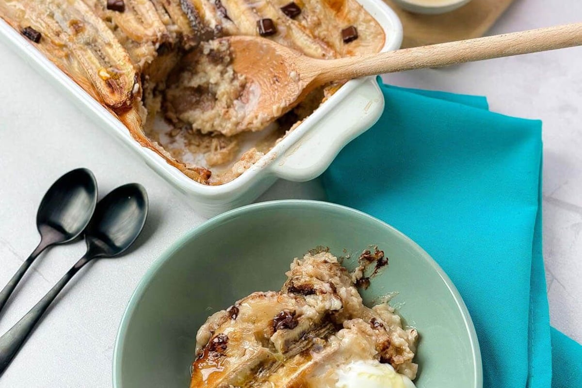 Baked banana dessert with chocolate chips served with cream and honey on a teal napkin