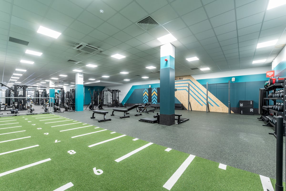 PureGym London Ilford: Turf area, resistance machines, weight racks, lifting platforms in a commercial gym setting.