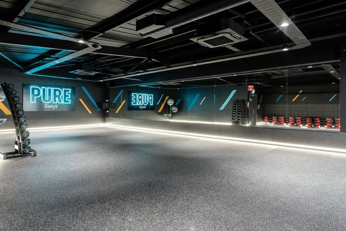 PureGym Northallerton: Rows of bright neon-lit equipment areas, treadmills, free weights, and mirrored walls.