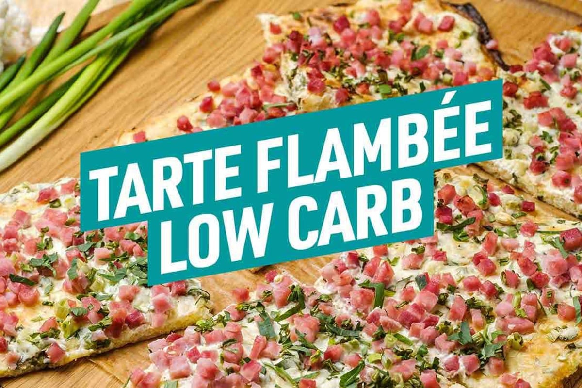 Tarte flambée tranchée garnie de jambon, herbes et oignons verts sur planche en bois