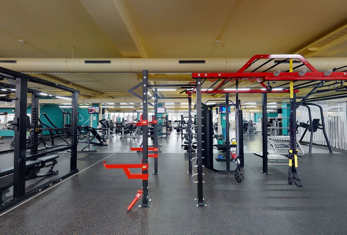 PureGym Winterthur Grüze: Fitnessstudio mit Krafttrainingsgeräten, Kabelgeräten, gummiertem Boden und verspiegelten Wänden.