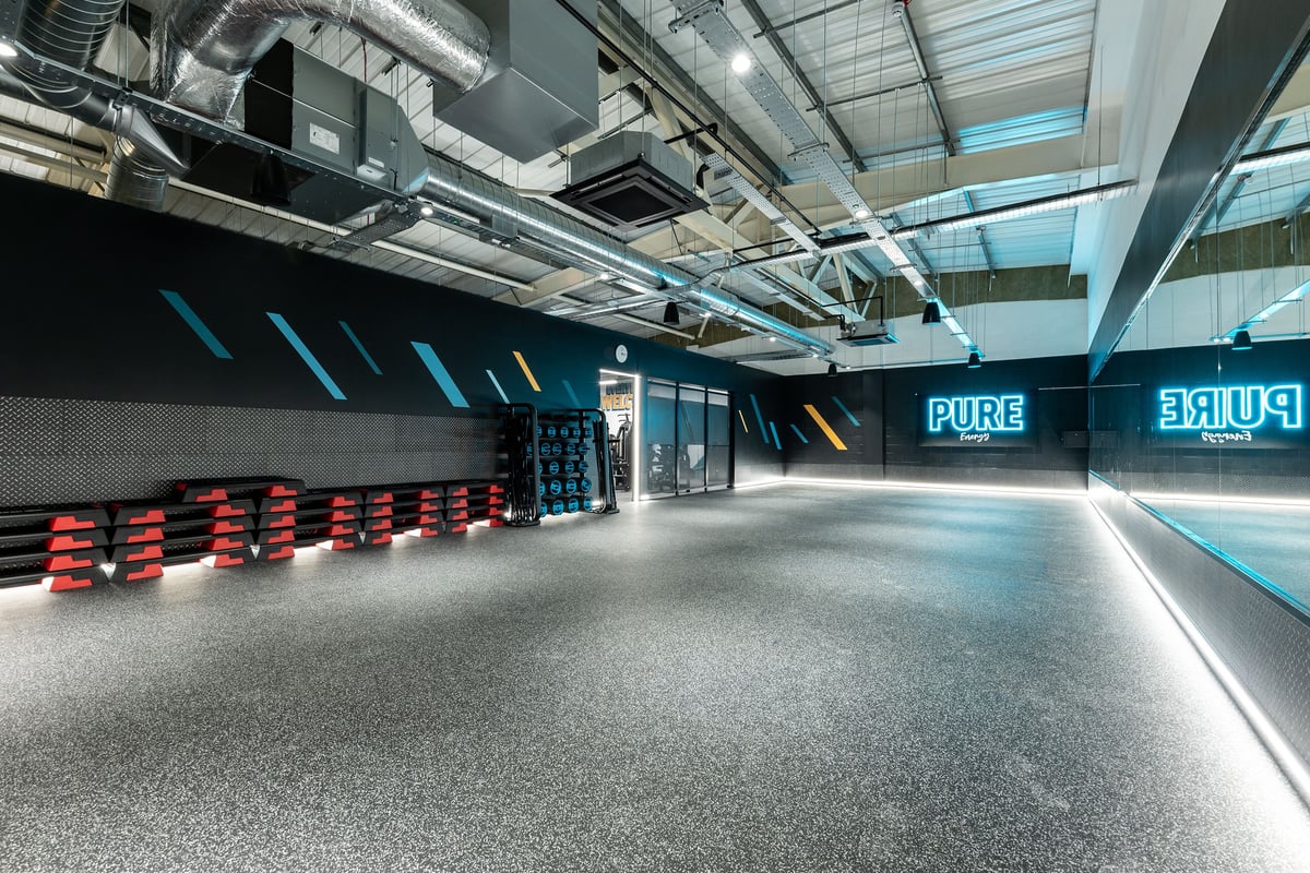 PureGym Shrewsbury Meole Brace: Rows of red exercise balls, mirrored walls, exposed ductwork and piping overhead.