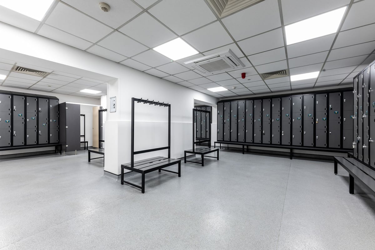 PureGym Luton And Dunstable: Rows of lockers, benches, and open floor space with tiled flooring.