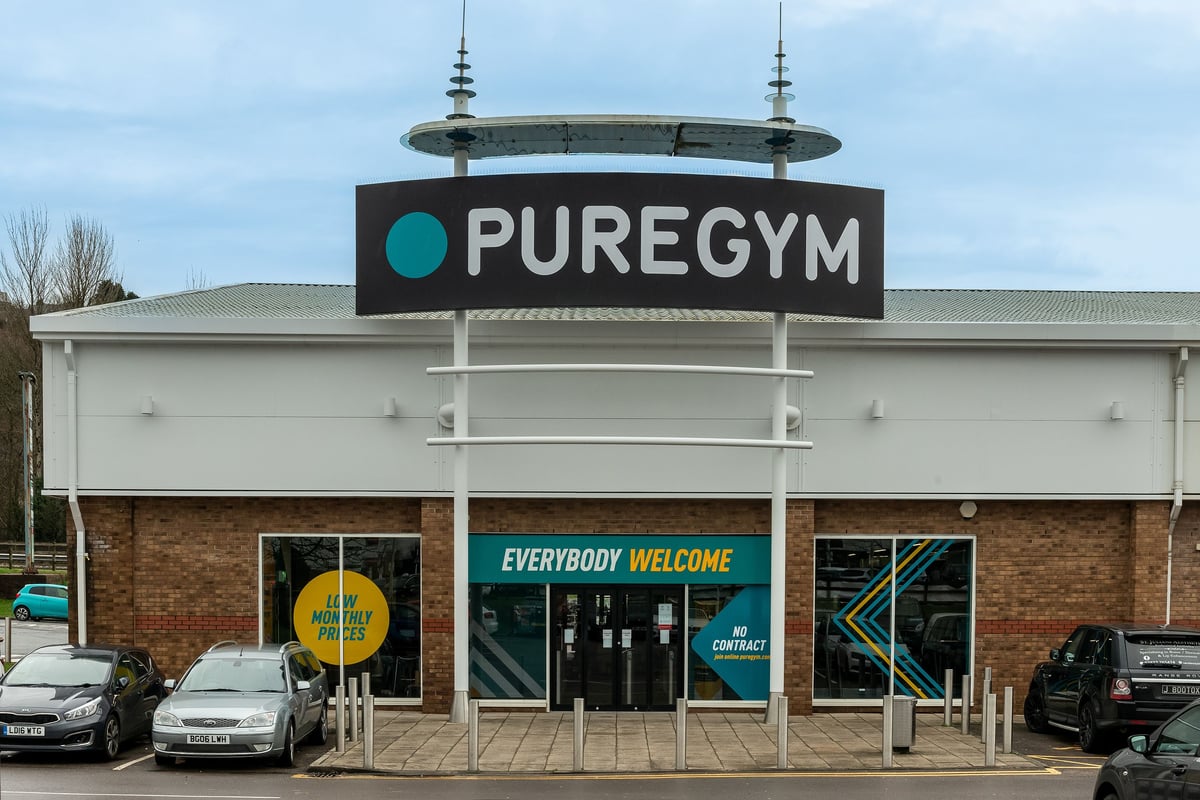 PureGym Llantrisant: PureGym storefront with branded signage, parked cars, and 'Everybody Welcome' window displays.