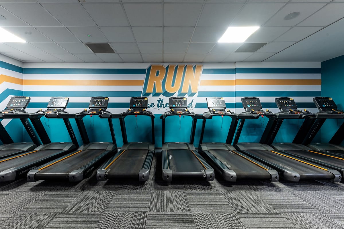 PureGym Purley: Rows of treadmills inside a brightly lit room with colourful wall branding.