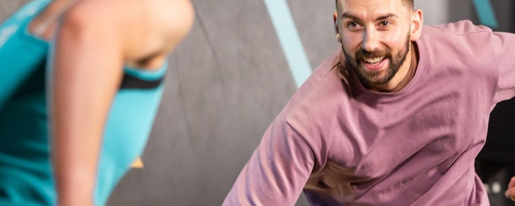 Man in pink top and woman in turquoise top exercising together on gym mats
