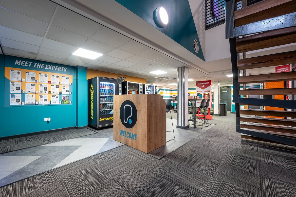 PureGym London Marylebone: Entrance area with wall signage, welcome podium, and vending machines with food and drink.