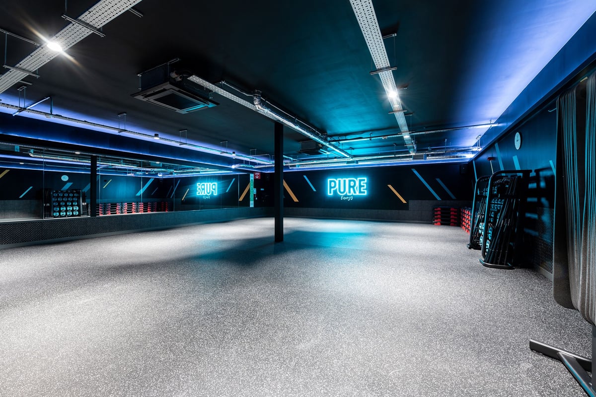 PureGym Ashford Warren Retail Park: Empty gym studio, blue neon lighting, mirrored walls, workout equipment.