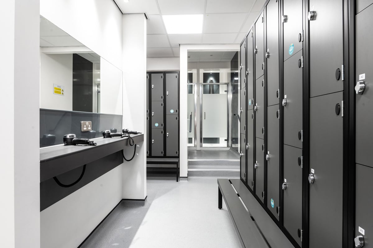 PureGym Cirencester: Rows of grey lockers, sink counter, and tiled floors - appears to be a changing room facility.