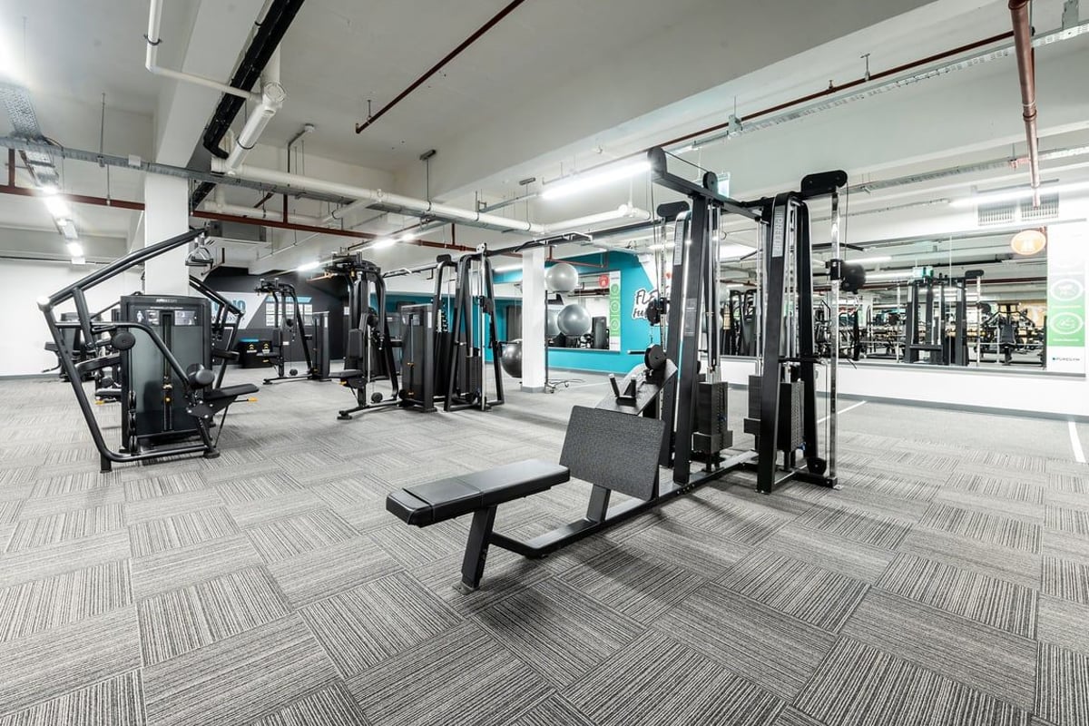 PureGym Gravesend: Resistance training machines, weighted stations, benches, rubberised flooring in a spacious gym area.