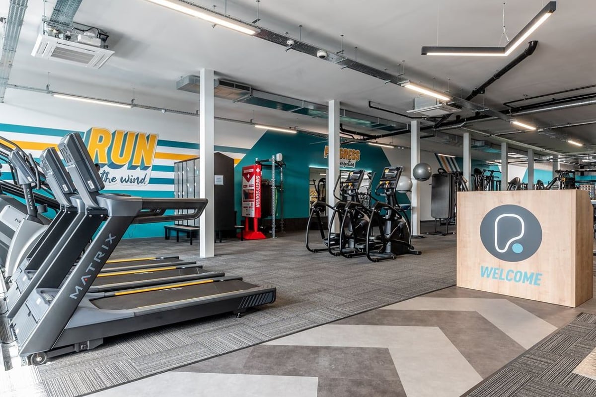 PureGym Sittingbourne: Treadmills, exercise bikes, weight racks, teal branding, and wooden welcome sign.