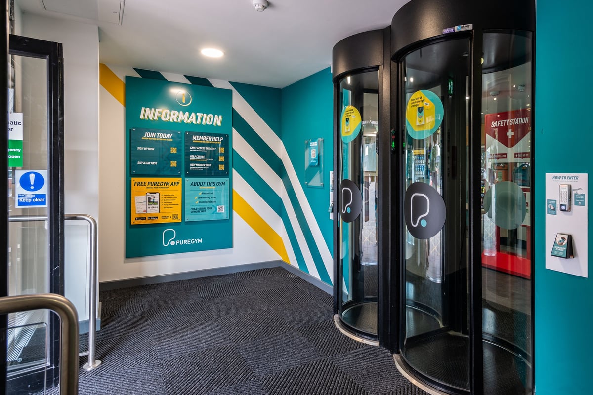 PureGym Northwich: Revolving doors, information signage, and a teal-accented interior space.