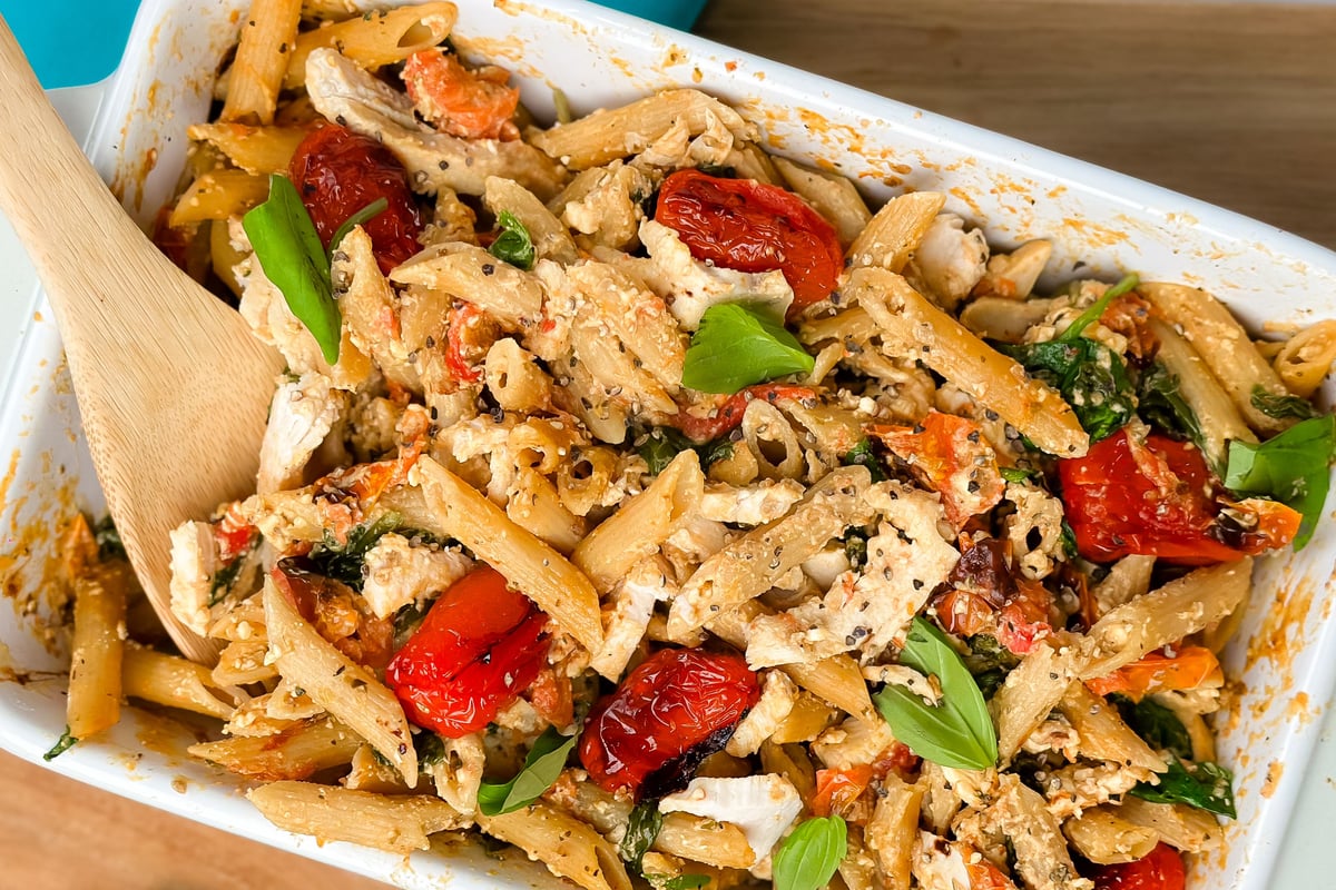 Pasta with tuna, roasted red peppers, spinach and cheese in white baking dish