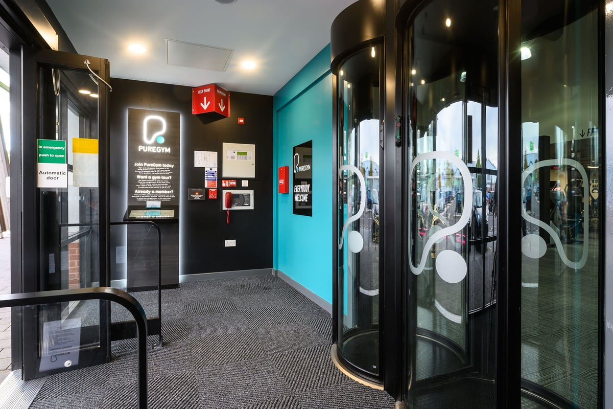 PureGym Bristol Abbey Wood Retail Park: Self-service kiosks, glass entry pods, and teal-coloured walls.