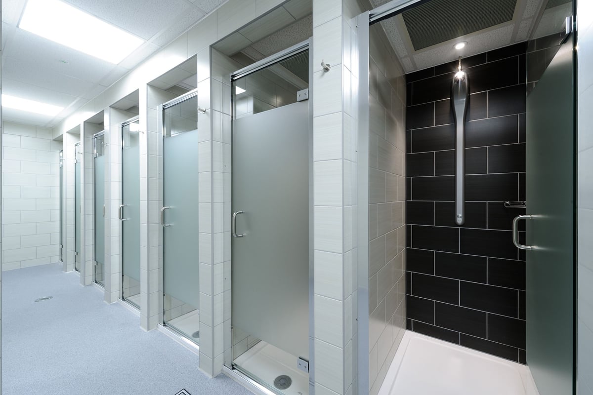 PureGym Billericay: Rows of shower cubicles with frosted glass doors and tiled walls.