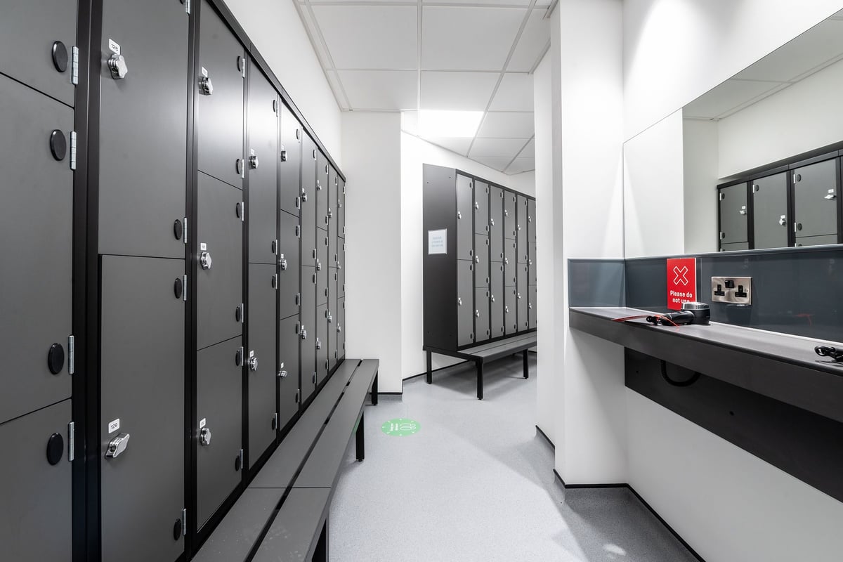 PureGym London Twickenham: Locker room with rows of metal lockers, benches, and a shoe rack.