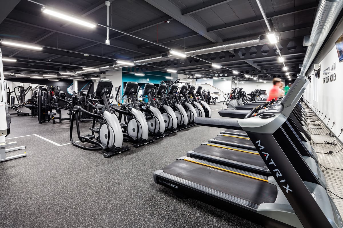 PureGym Manchester Stretford: Rows of treadmills, ellipticals, and exercise bikes in a brightly lit gym interior.