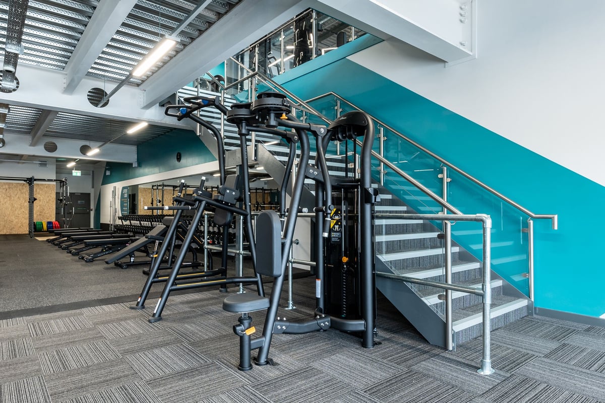 PureGym Yate: Stair climber machinery, weight racks, free weights, and mirrored walls in a gym facility.