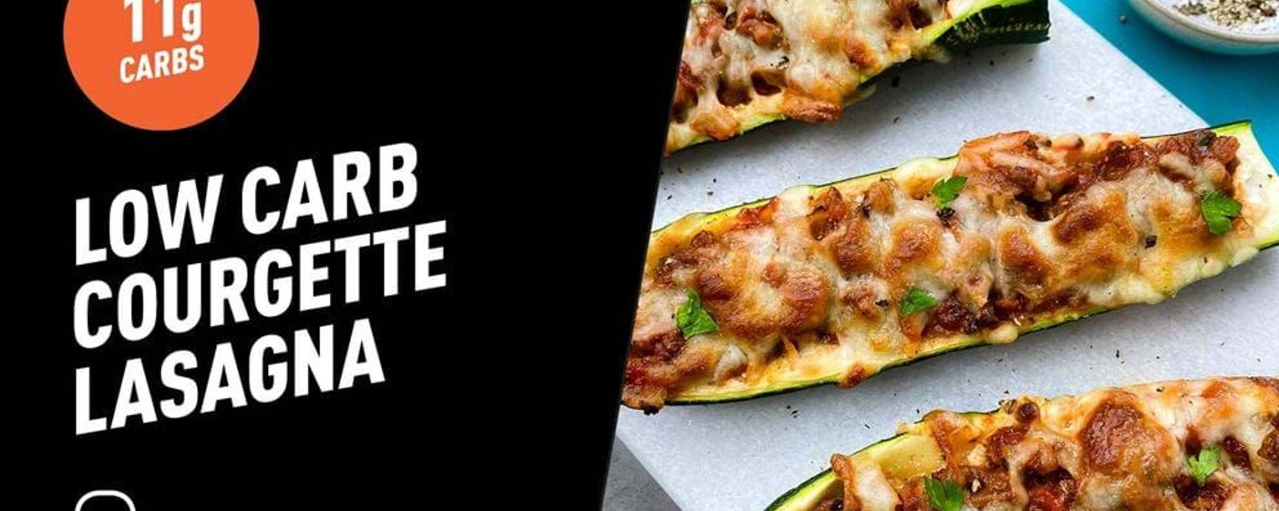 Three baked courgette halves topped with minced meat, melted cheese, and herbs on parchmen