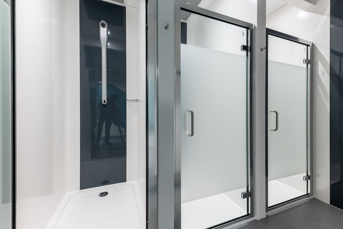 PureGym Merthyr Tydfil: Glass-enclosed shower cubicles with pivot doors and handle rails.