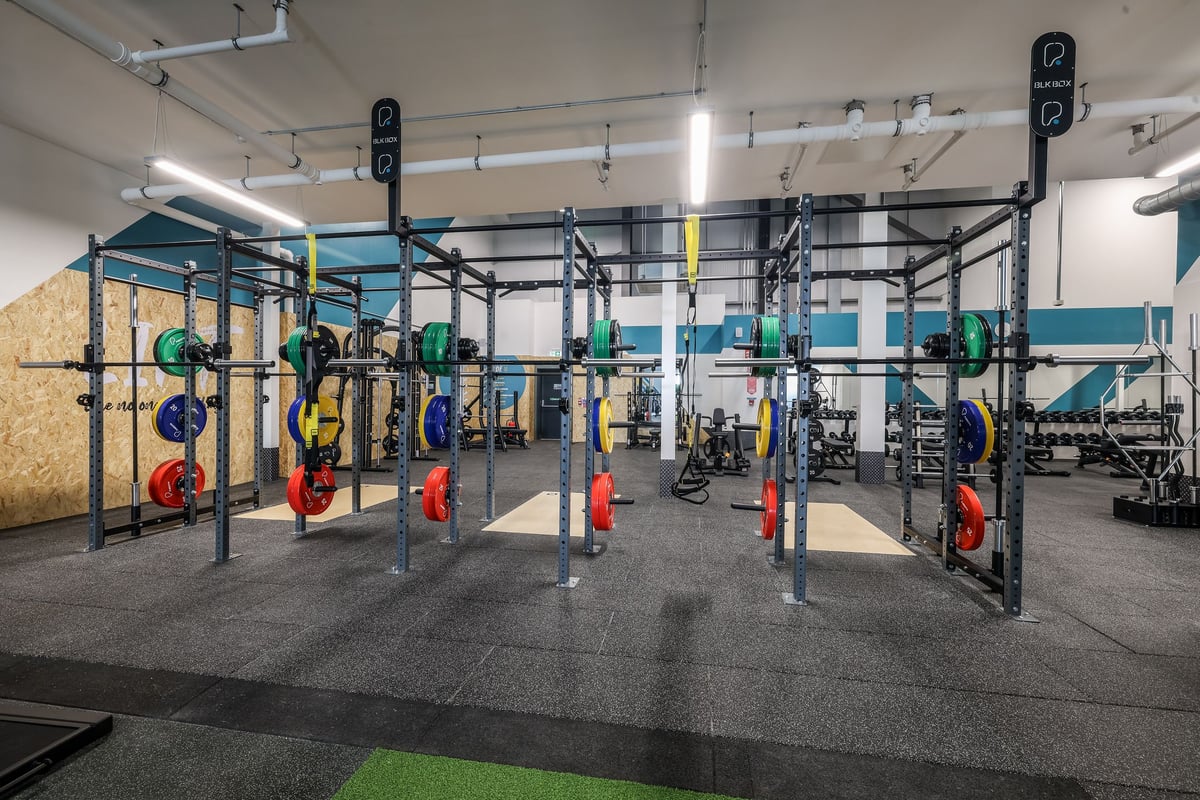 PureGym Bishop Auckland: Rows of squat racks, weight plates in various colours, rubberized flooring.