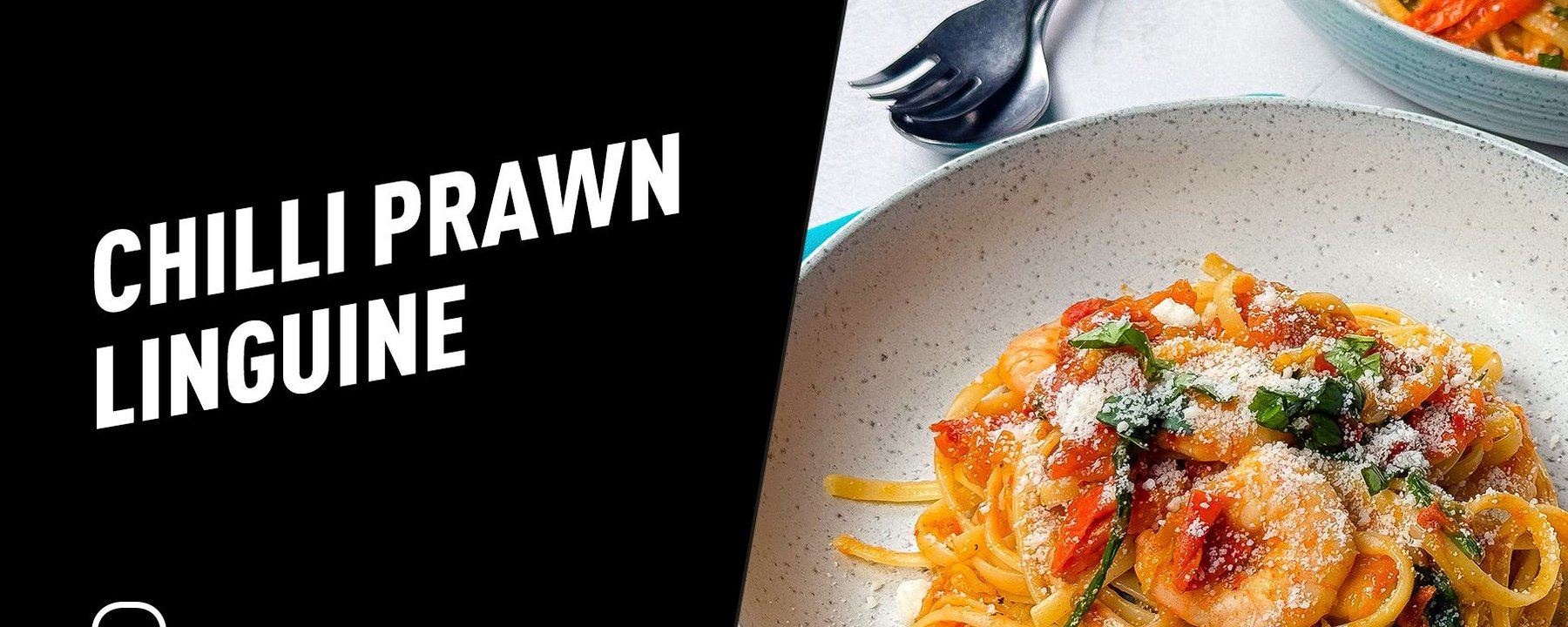 Chilli prawn linguine with grated cheese and herbs served in a bowl with cutlery nearby