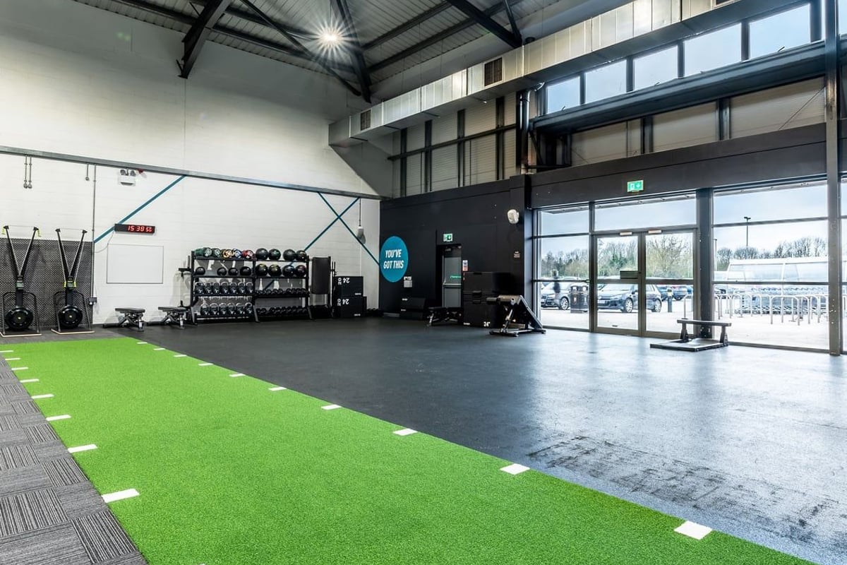 PureGym Leeds Hunslet: Gym space with resistance machines, green turf area, free weights, and floor markings.