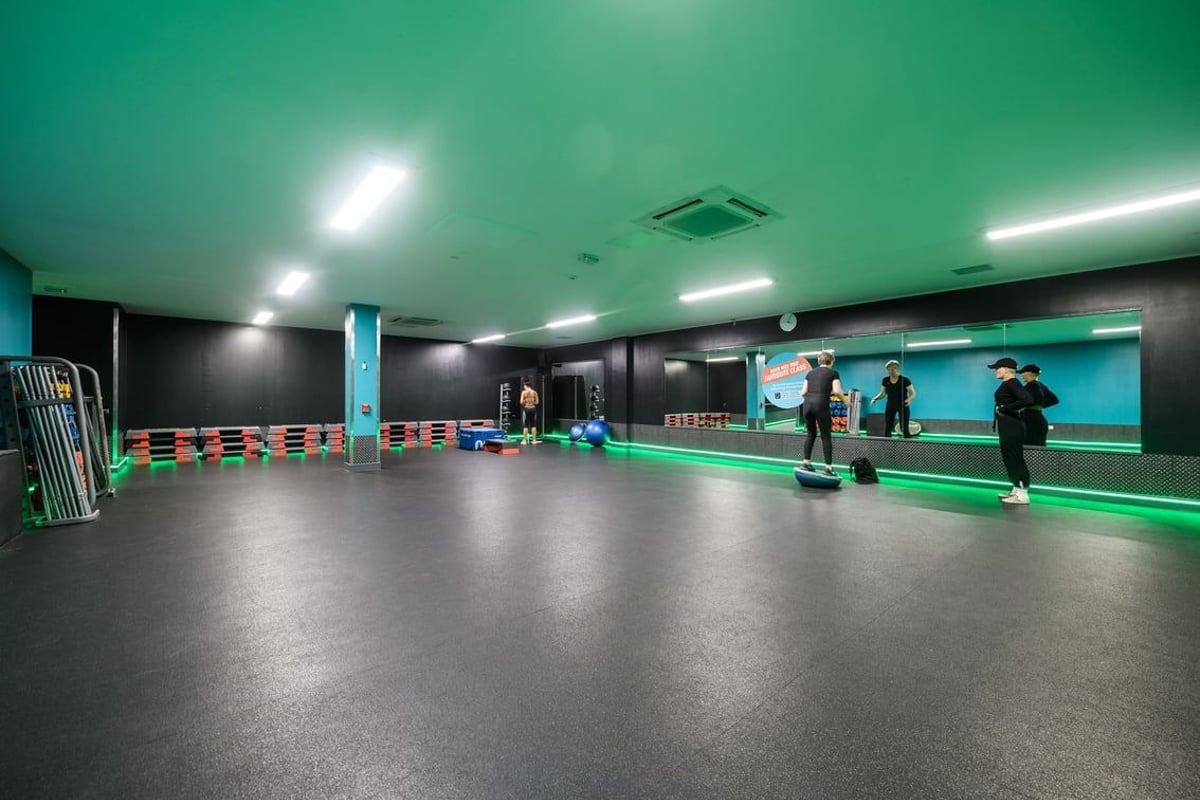 PureGym Newcastle Longbenton: Obstacle course area with barriers, turf flooring, and large video screen wall.