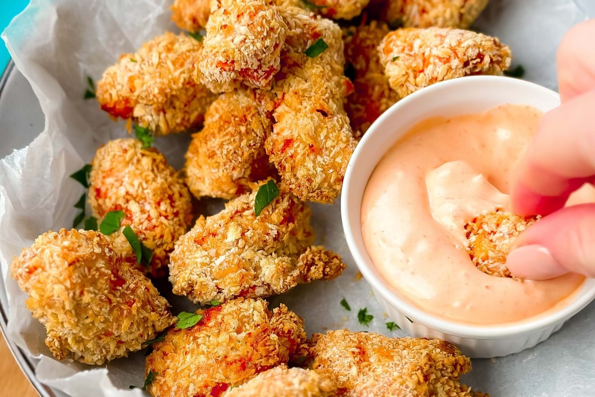 Breaded chicken nuggets with dipping sauce on parchment paper in a bowl