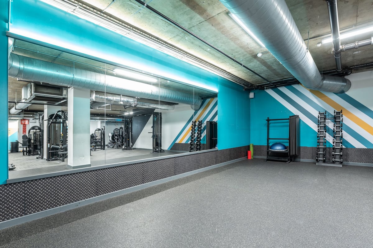 PureGym London Swiss Cottage: Weight racks, free weights, rubberized flooring, and tubing in a colourful gym area.