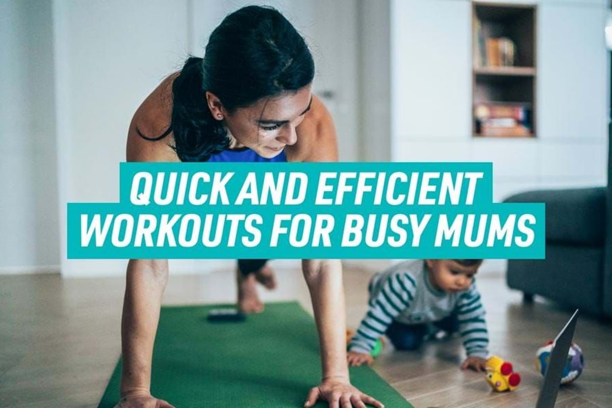 Woman doing plank exercise on yoga mat with toddler playing nearby on floor