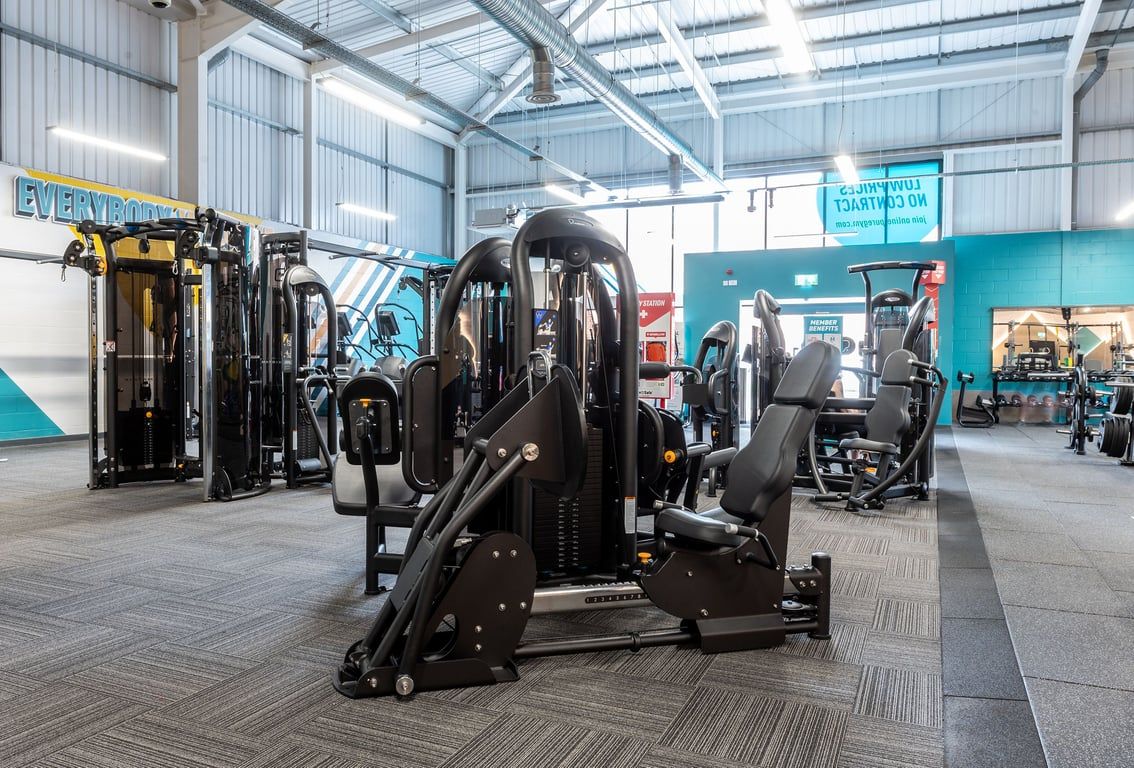 PureGym Spalding: Rows of resistance machines, benches, and cable crossover units in a bright industrial gym space.