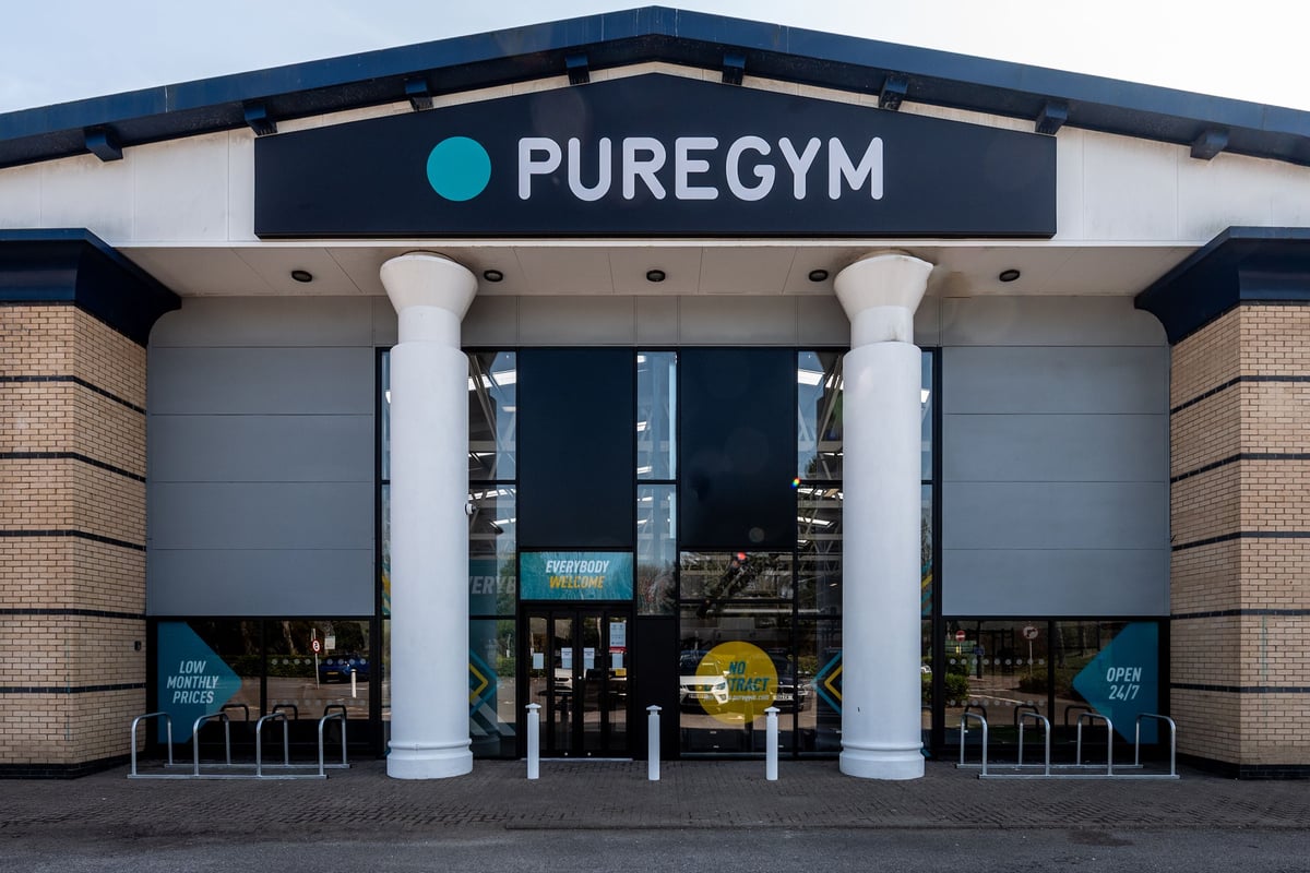 PureGym Bridgend: Gym exterior with pillars, large windows showcasing equipment inside.