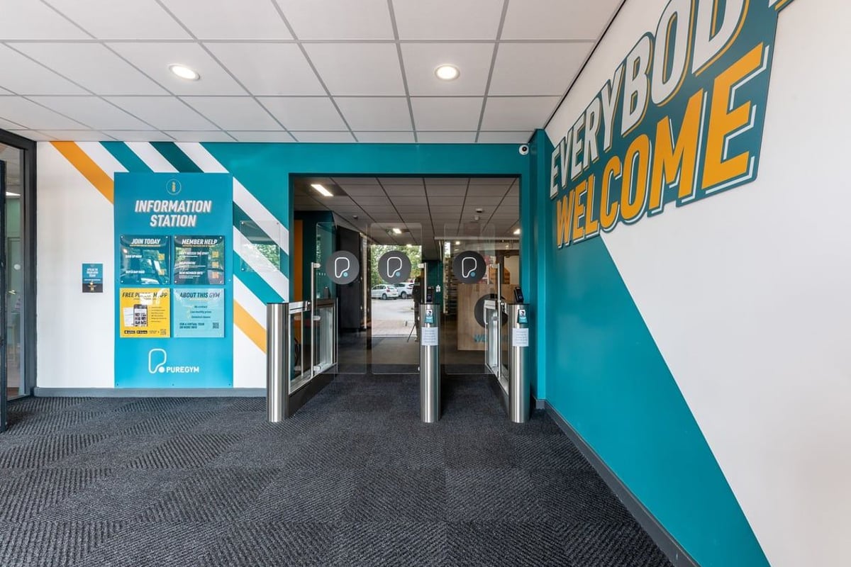 PureGym Sheffield Crystal Peaks: Entrance area with teal welcome signage, information station, and turnstiles.
