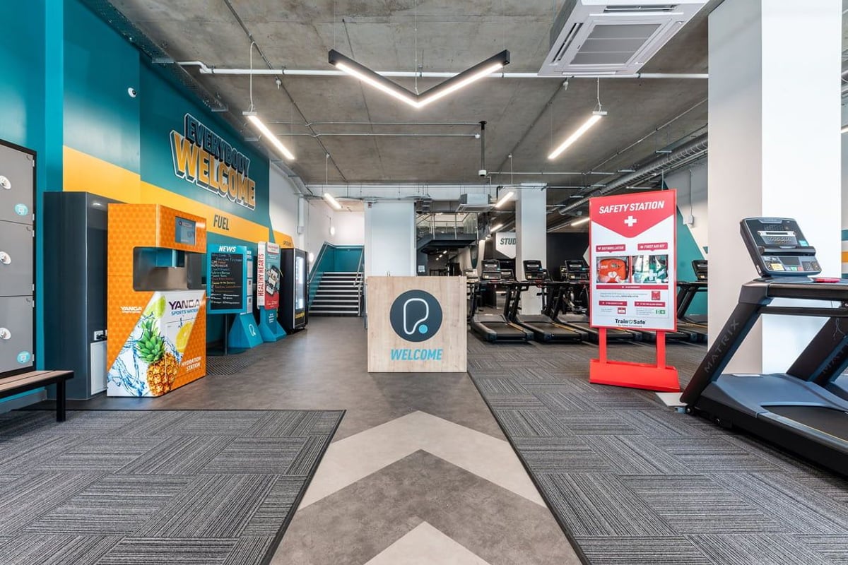 PureGym London Feltham: Treadmills, ellipticals, self-service kiosks, signage with fitness promotions.