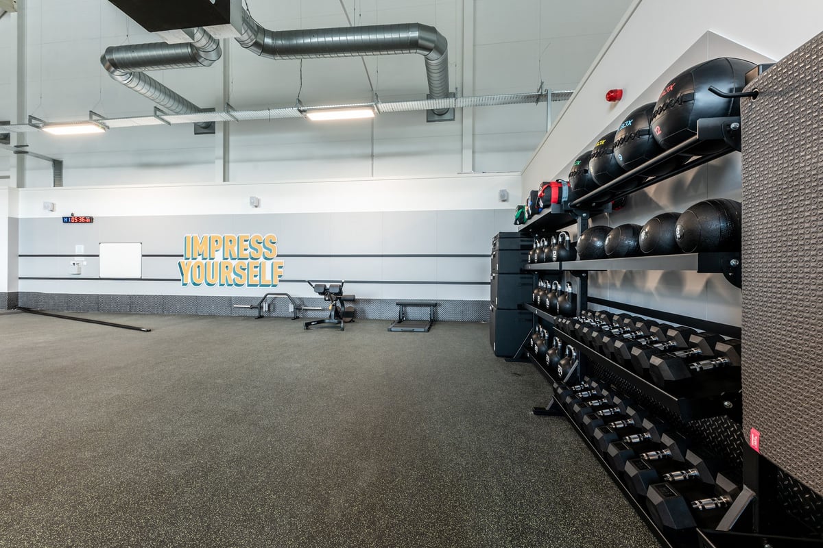 PureGym St Ives Cambridgeshire: Rows of dumbbell racks, kettlebells, and weight benches on rubberized flooring.