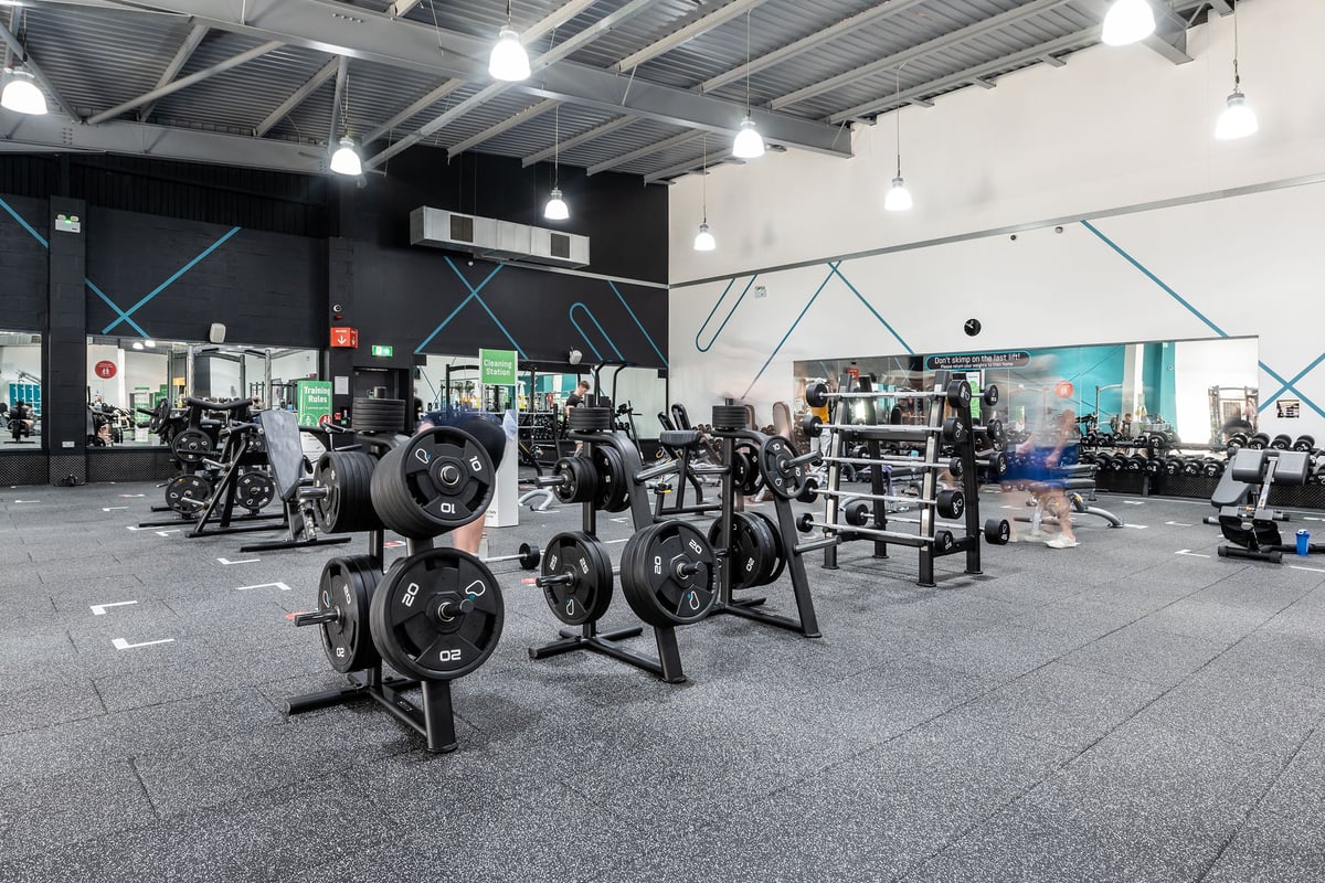 PureGym Warrington Central: Free weights, weight racks, rubberized flooring, and exercise equipment in a modern gym setting.