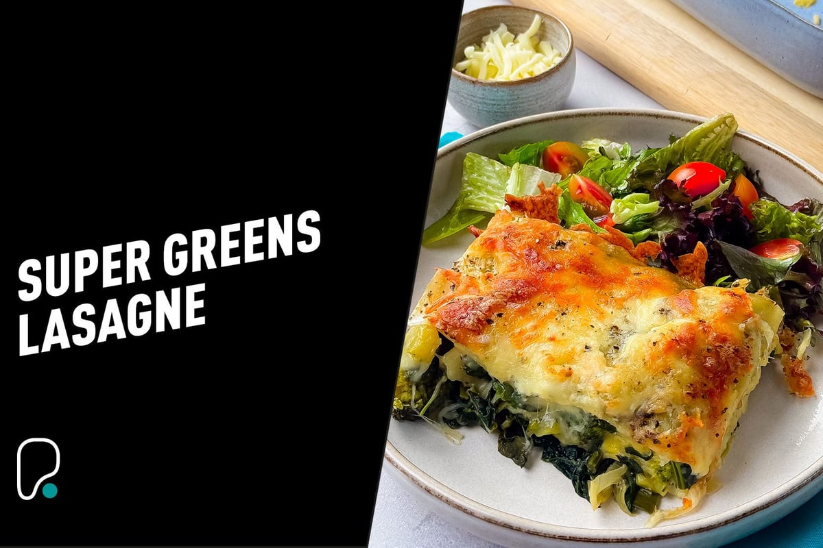 Baked super greens lasagne slice with mixed salad and grated cheese in bowl