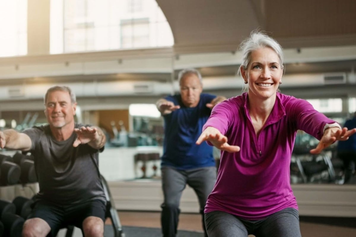 3 people squatting with their arms out