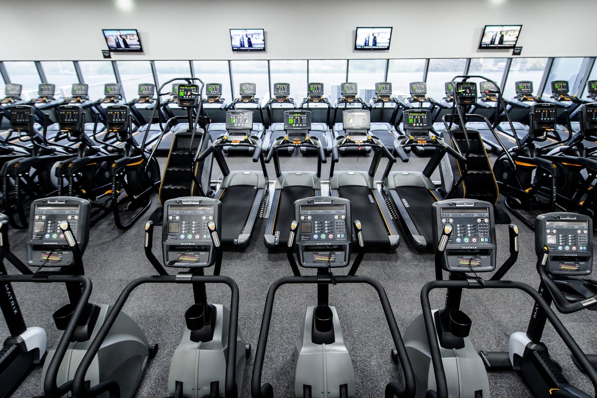 PureGym Bedford Heights: Rows of treadmills facing TV screens in a gym's cardio training area.
